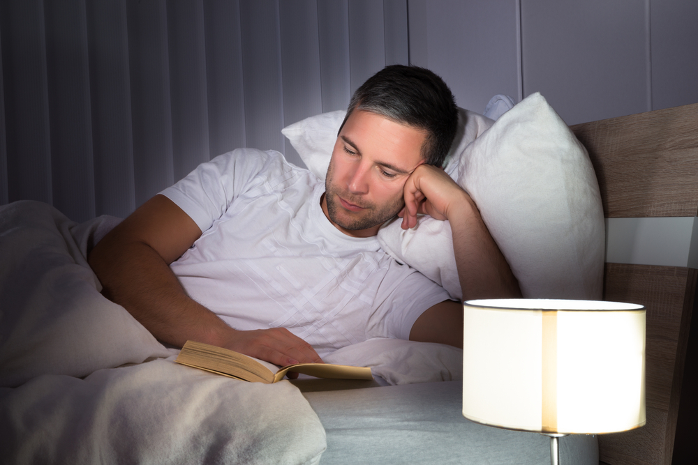 muškarac čita knjigu u krevetu