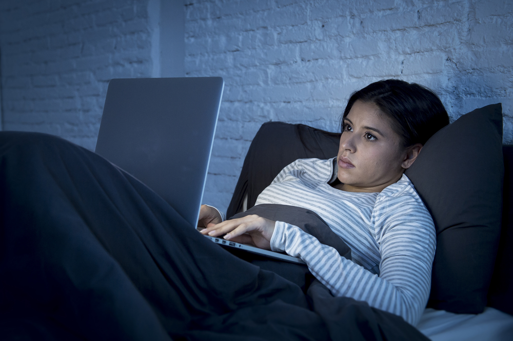 devojka gleda u laptop u krevetu